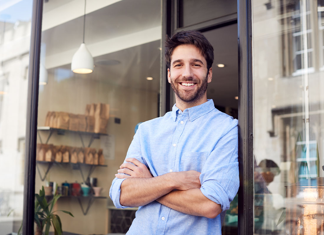Business Insurance - Smiling Business Man Standing in Front of Small Town Shop